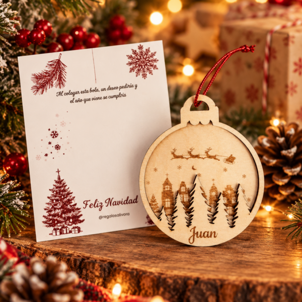 Bola de madera con nombre y paisaje de casas, árboles y trineo de Papá Noel.